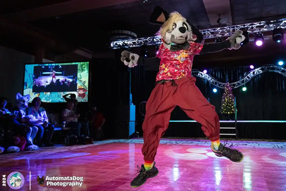 A person in a furry dog costume with blonde hair, wearing a red patterned shirt and red pants, is mid-dance move on a lit…