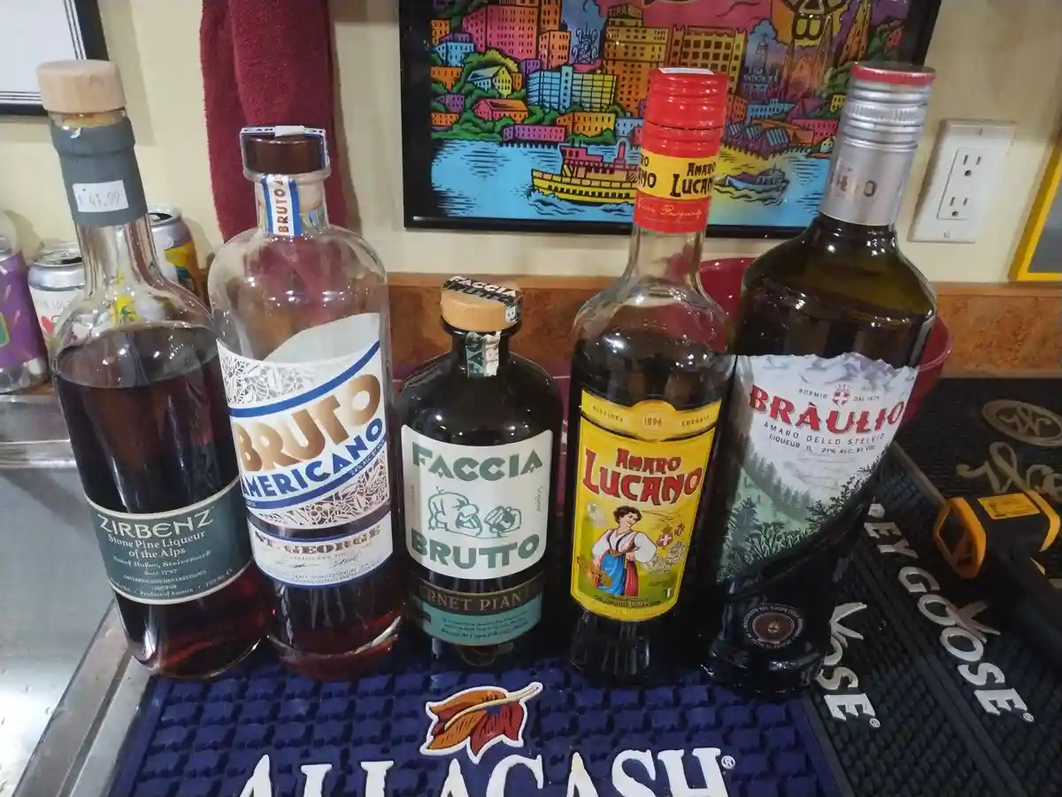 Five bottles of liqueur are lined up on a bar mat, each labeled with the word 'brutto' or a similar variant, including…