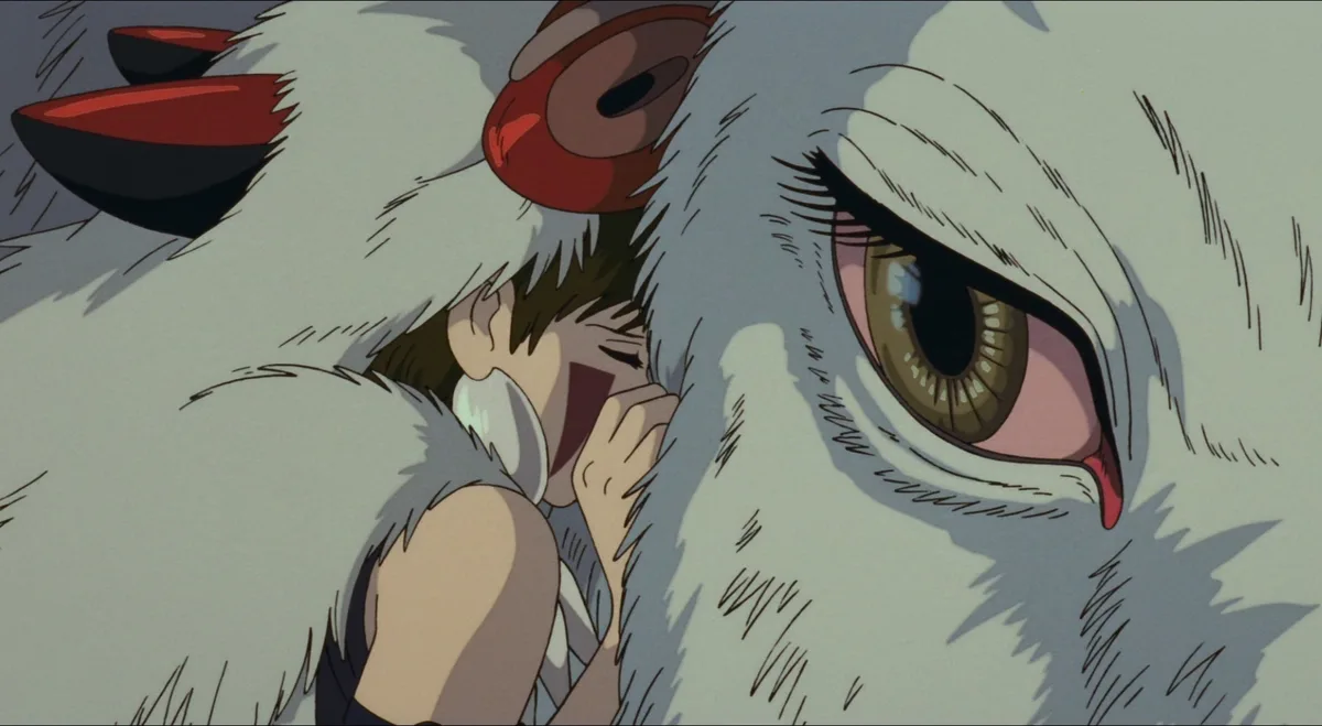 A close-up anime scene shows a young girl with brown hair hiding her face in the white, fluffy fur of a large creature with…