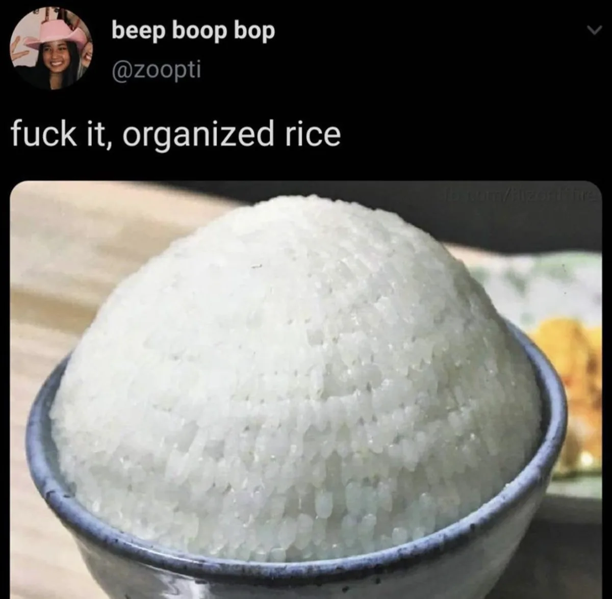 A close-up photo shows a perfectly molded, dome-shaped mound of white cooked rice in a dark ceramic bowl, presented as an…