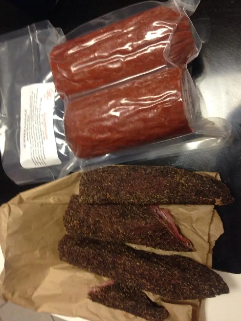 The image shows two distinct types of beef jerky: vacuum-sealed, uniform red packages from a store on top, and irregularly…