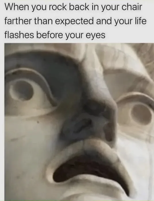 A close-up image of a stone statue's face, showing wide, startled eyes and an open mouth in a look of shock or horror. The…
