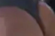 A blurry, low-resolution close-up image showing a person's bare buttocks, with a finger partially visible near the top…