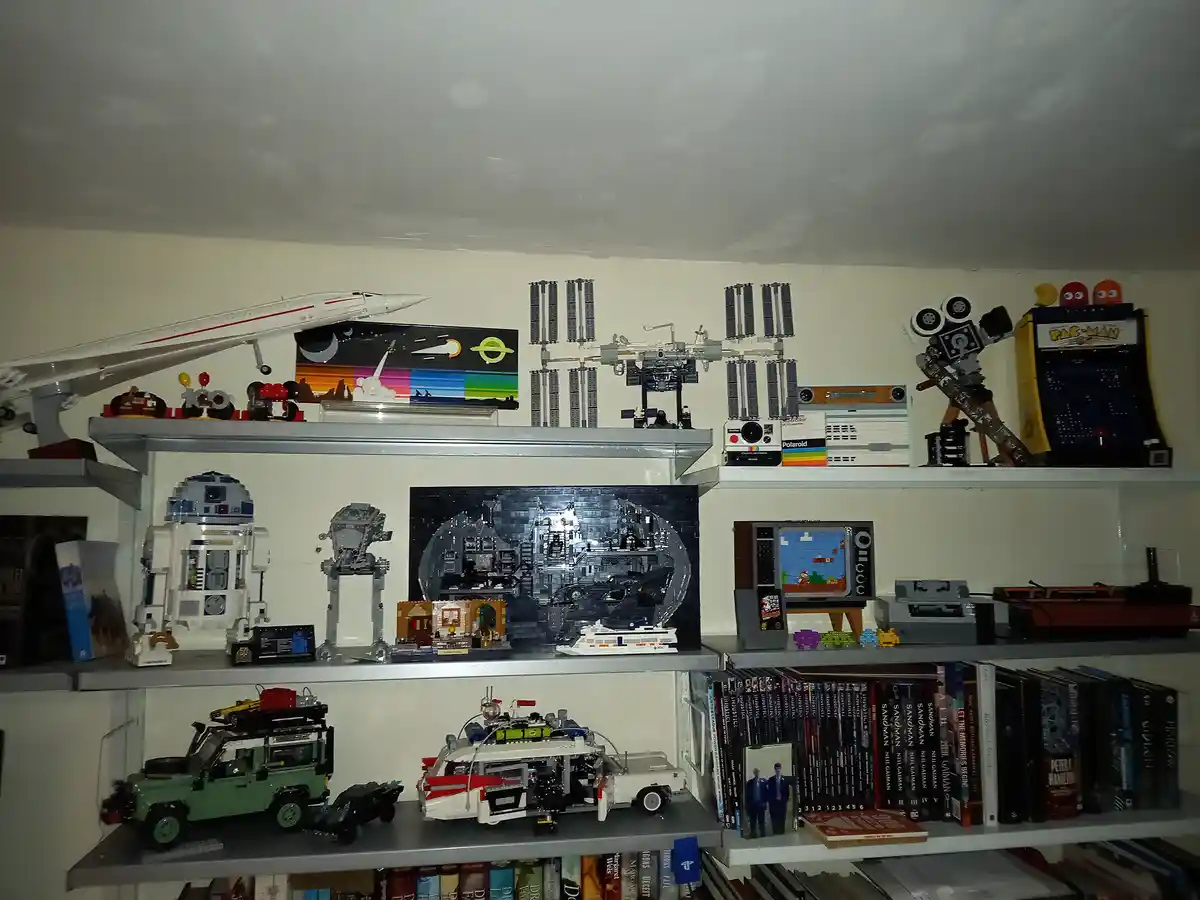 A photo of multiple shelves filled with intricate lego models including a space station, pac-man arcade machine, r2-d2…
