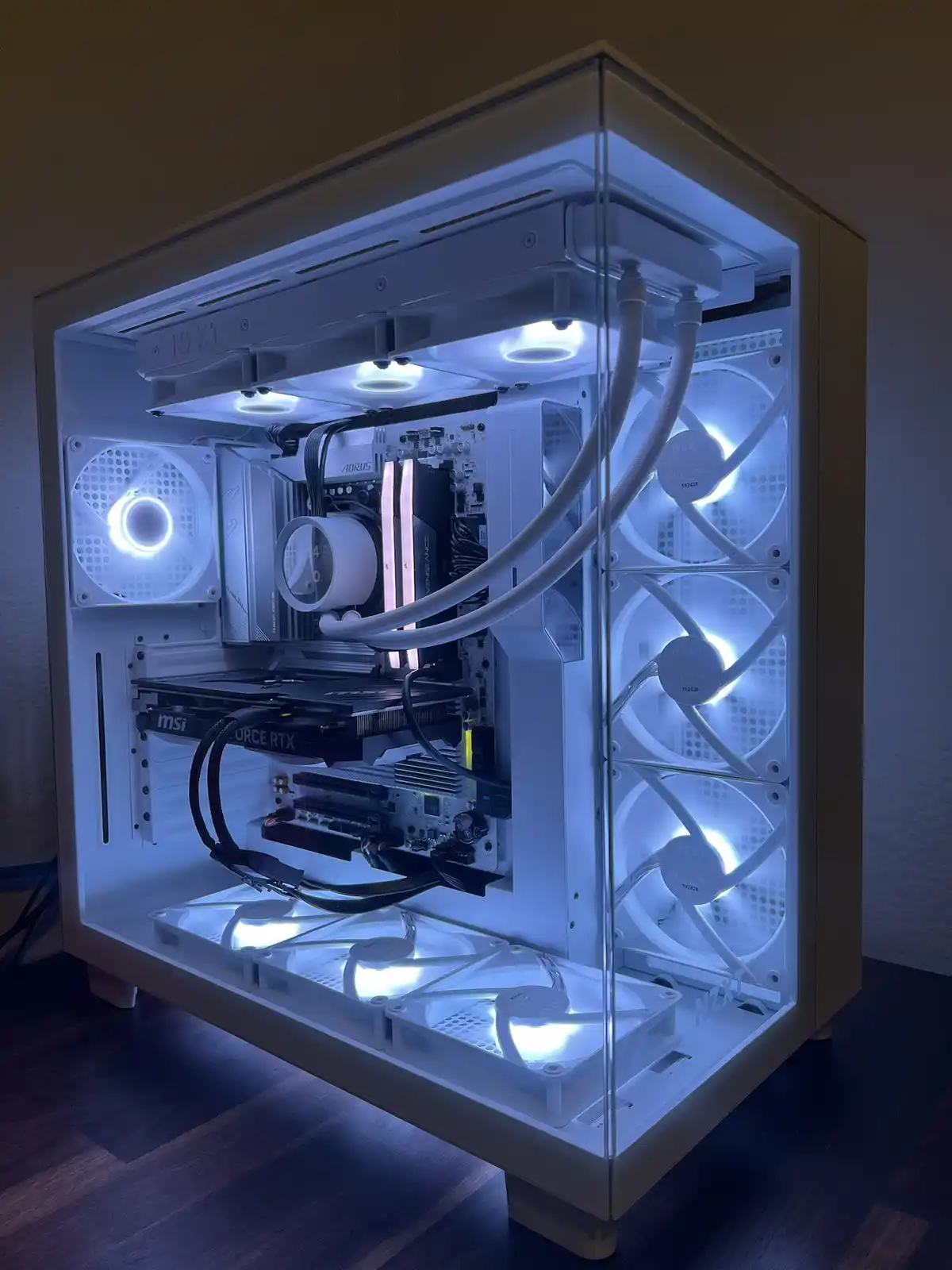 A white, fully transparent computer case with multiple glowing white fans and liquid cooling tubes, showcasing high-end…