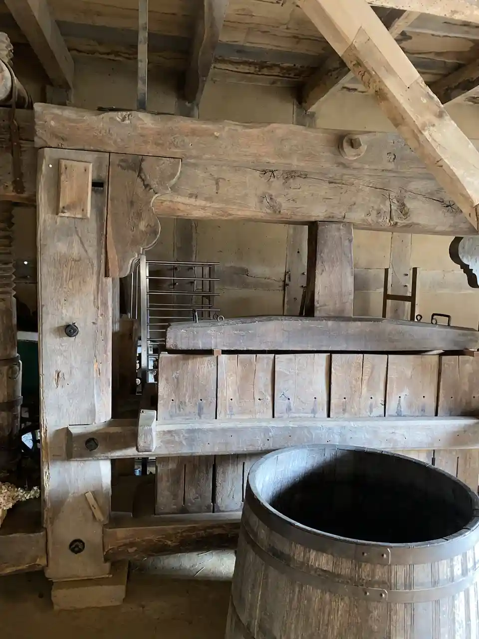 An old wooden wine press with a large barrel sits in a rustic room with exposed beams. The overlaid text reads 'i'm not…