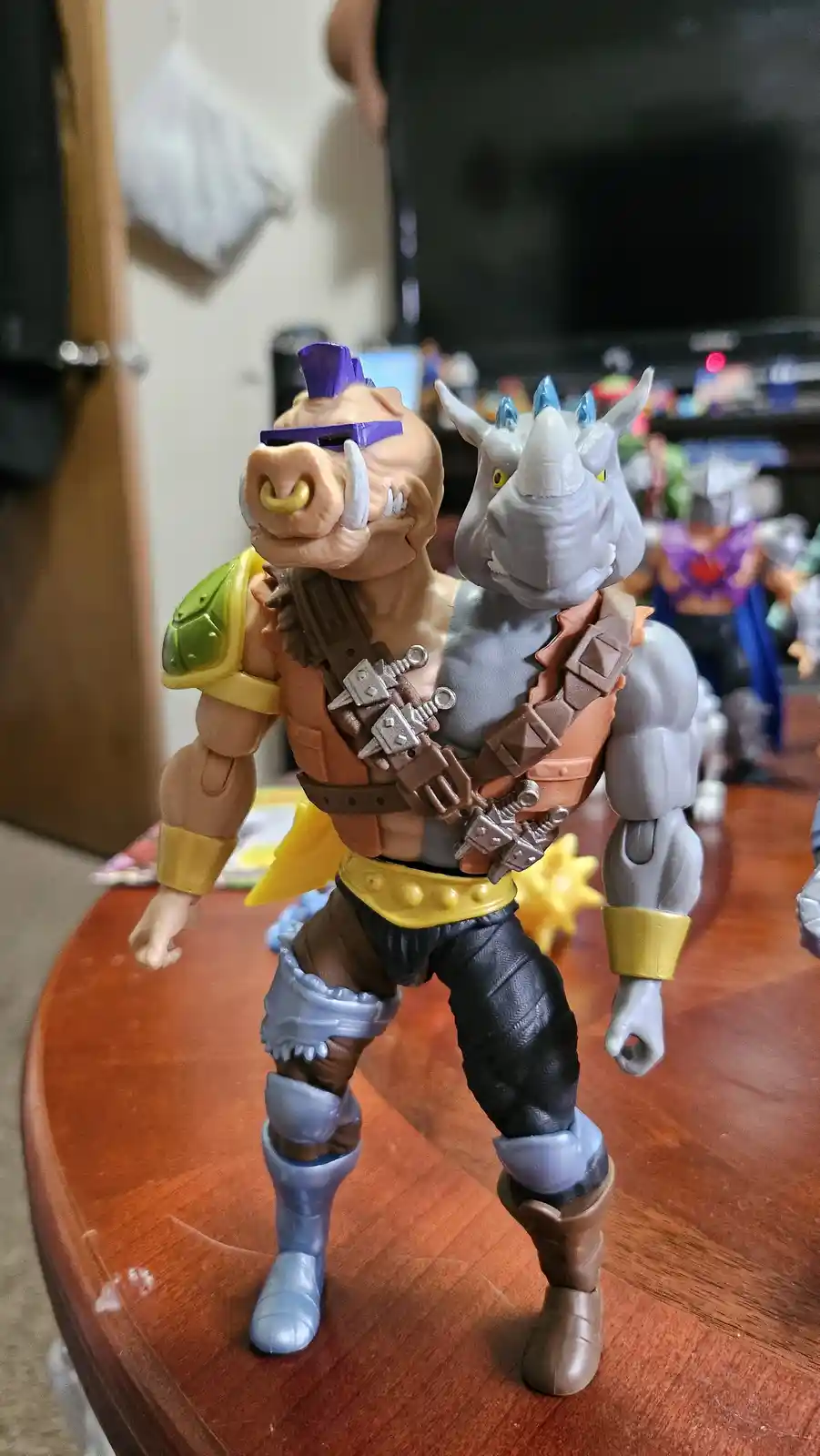 A custom action figure of a muscular humanoid with a pig's head on one side and a rhino's head on the other, wearing armor…