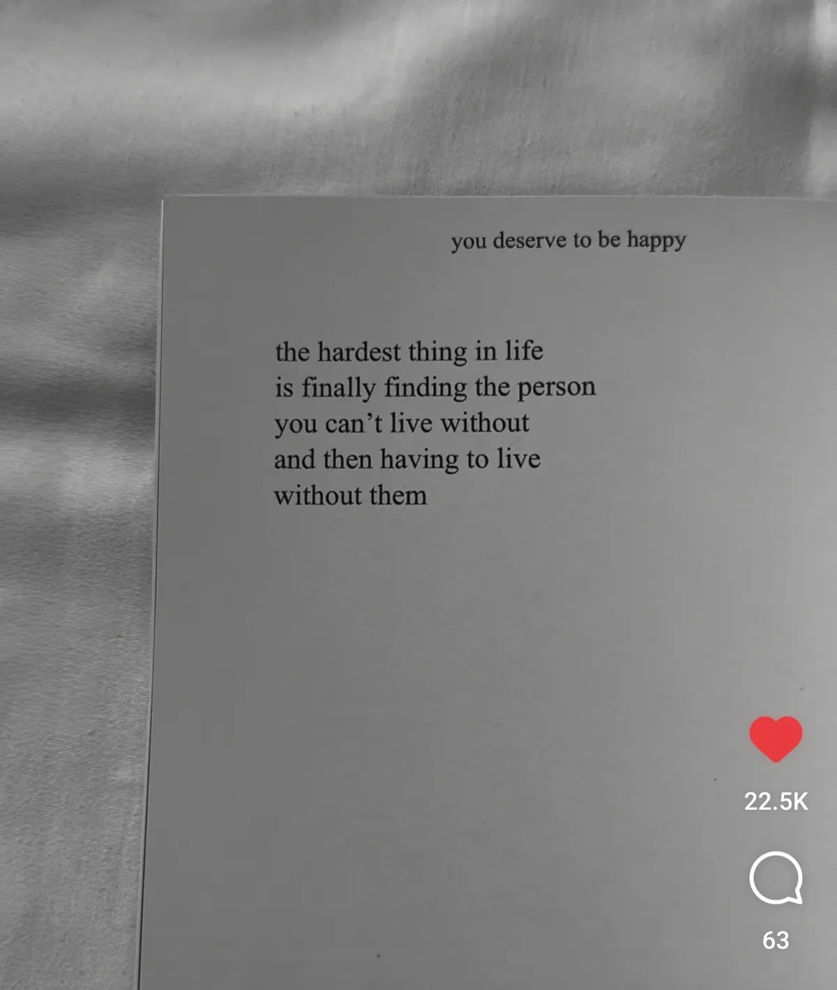 A black-and-white photo shows a piece of paper with text overlaid on a textured fabric background. The text reads 'you…
