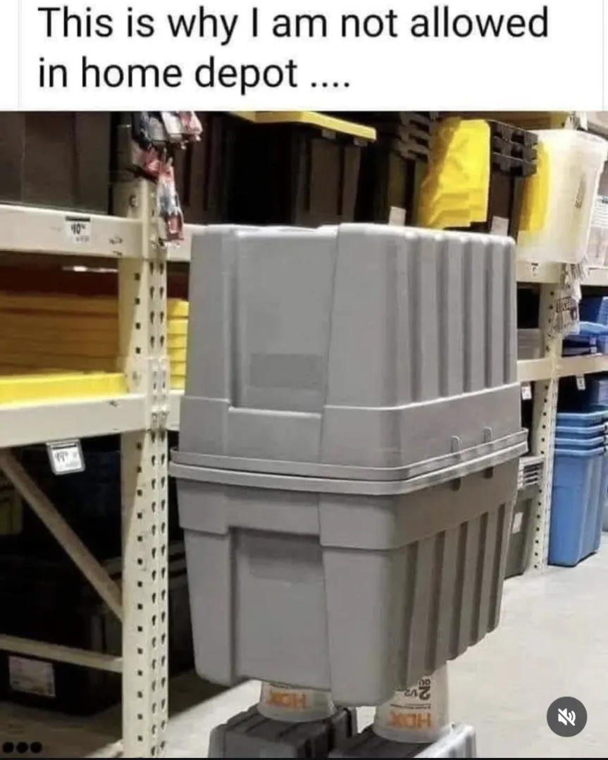 A photo of two gray plastic storage bins stacked vertically on top of each other inside a Home Depot aisle, with shelves and…