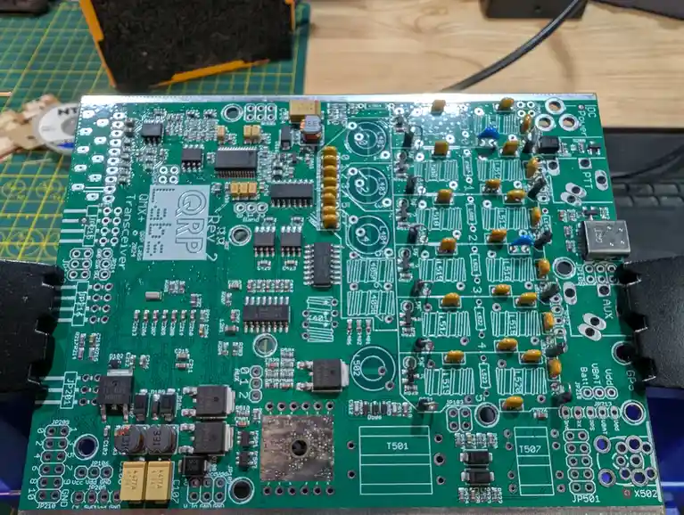 A close-up photo of a green printed circuit board (PCB) populated with numerous electronic components like resistors…