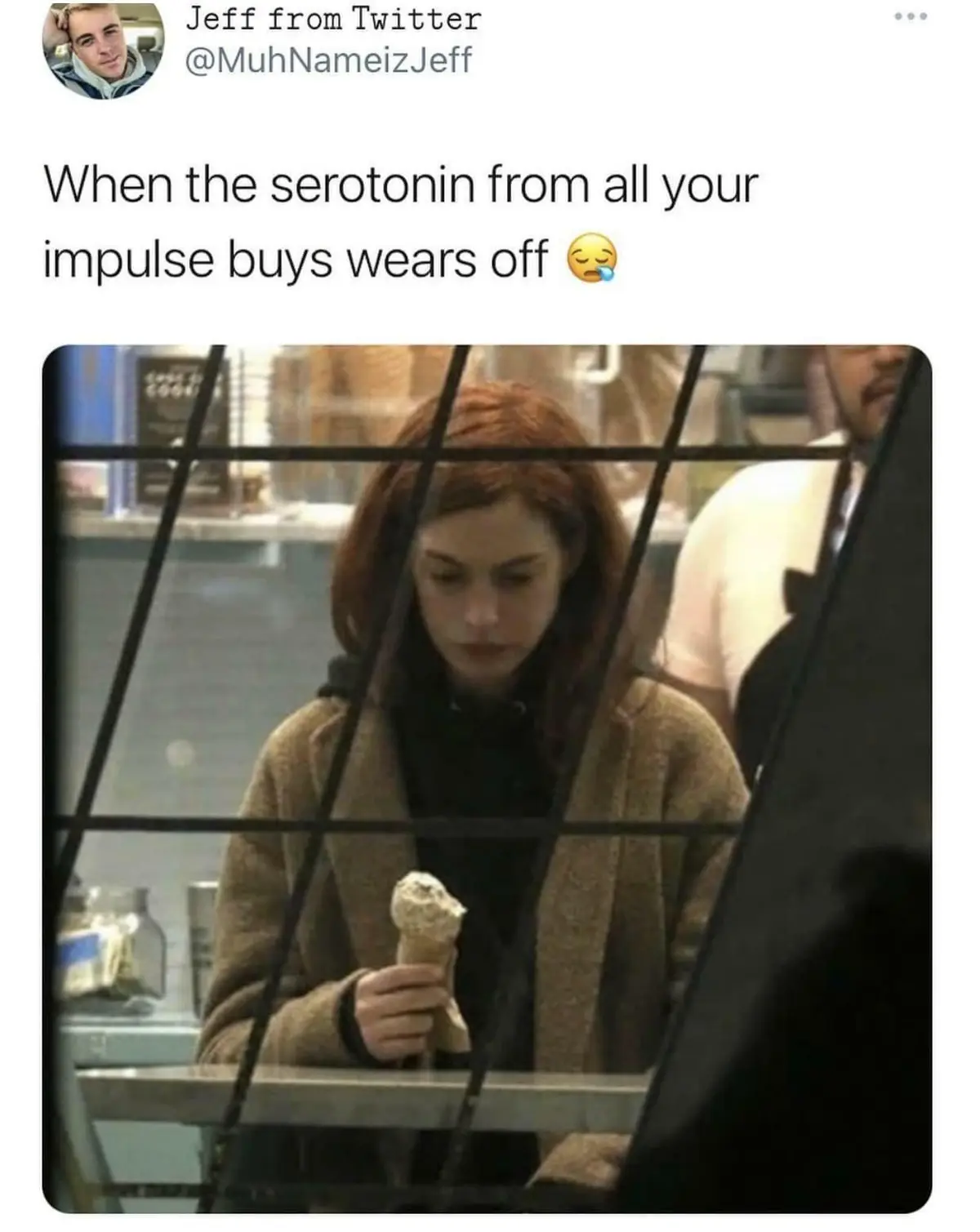 A woman with reddish-brown hair, wearing a beige coat over a black top, looks down sadly while holding a partially eaten ice…
