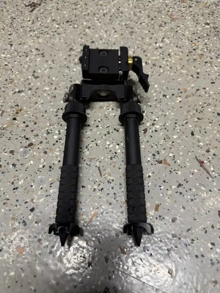 A black camera tripod with two legs and a mounting plate lies on a speckled gray floor. The overlaid text reads 'i'm not a…