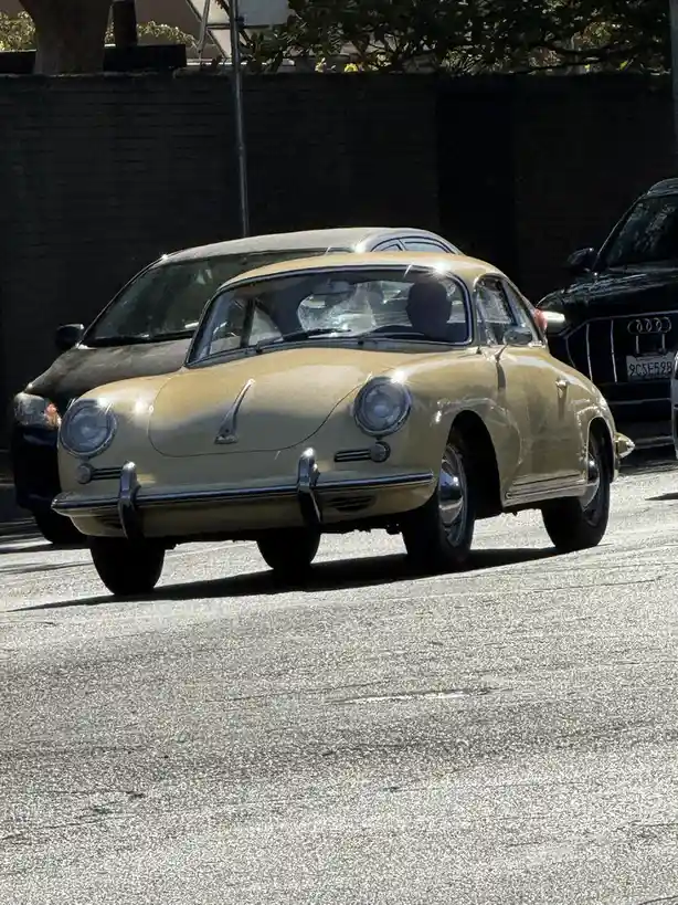 A vintage beige Porsche 356 is parked on a street, with modern cars visible behind it. The overlaid text reads 'i'm not a…