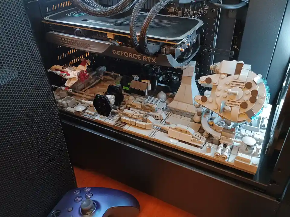 The image shows the interior of a computer case with a custom-built Lego Millennium Falcon model constructed on the…