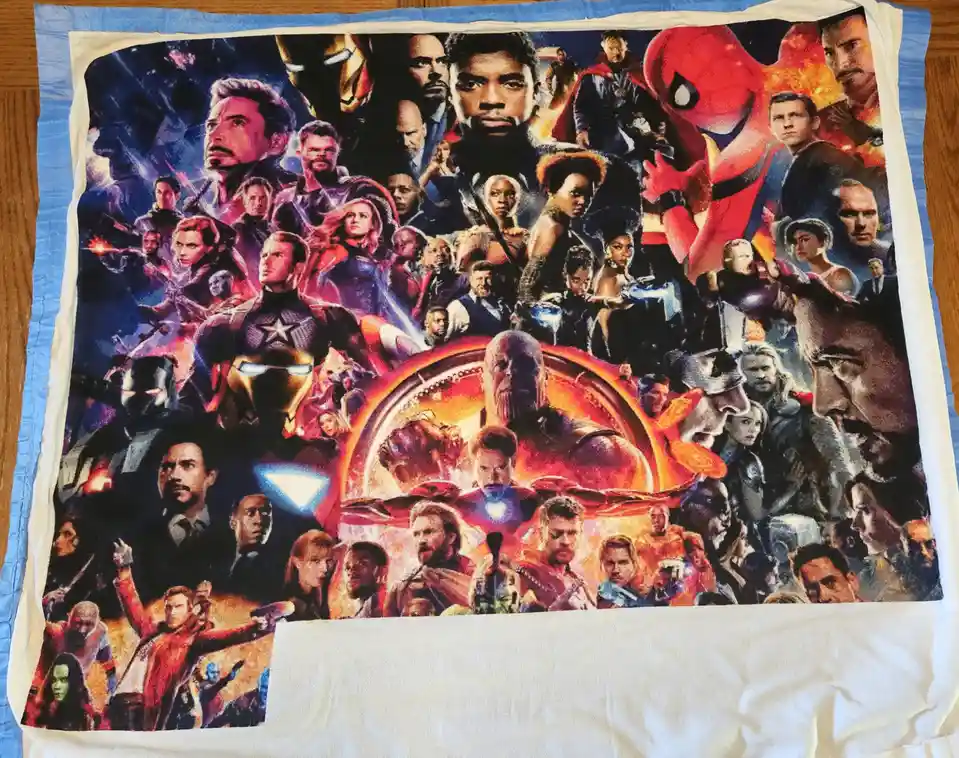 A close-up of a fleece blanket featuring the 'Avengers: Endgame' movie poster, showing a dense collage of Marvel superheroes…