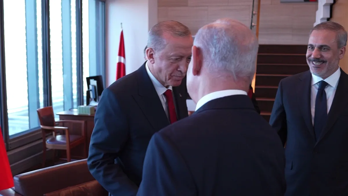 Three men in suits are in an office with a Turkish flag visible; one man leans in to speak to another whose back is to the…