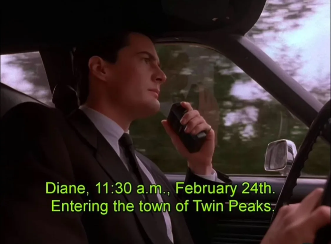 A man in a suit sits in a car, holding a radio microphone, looking forward. Green text at the bottom reads 'Diane, 11:30…