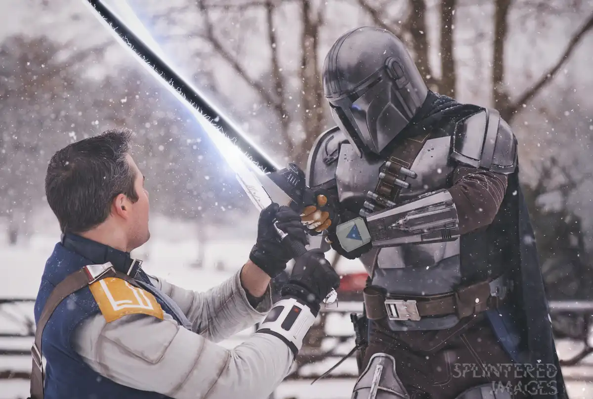 Two people in Star Wars cosplay are locked in a lightsaber duel outdoors in the snow. One is dressed as a Mandalorian in…