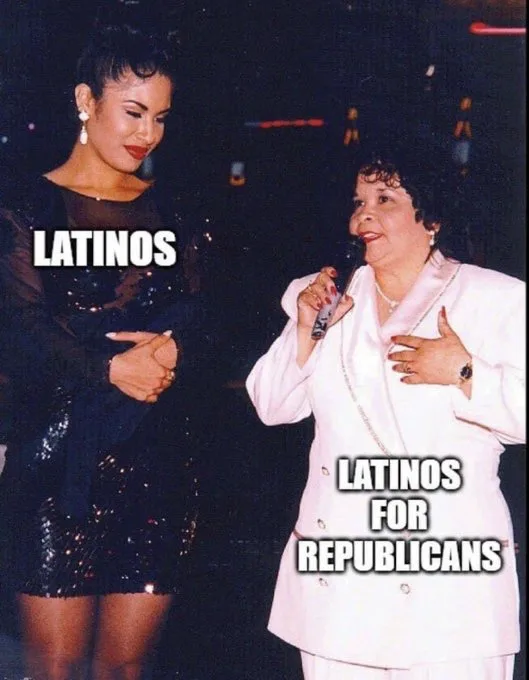 Two women stand side by side on a stage; the woman on the left wears a black sequined dress and has the word 'LATINOS'…