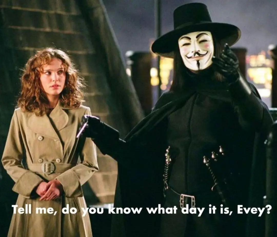 A still from the movie V for Vendetta shows a man in a black cloak and Guy Fawkes mask pointing at a woman in a beige trench…