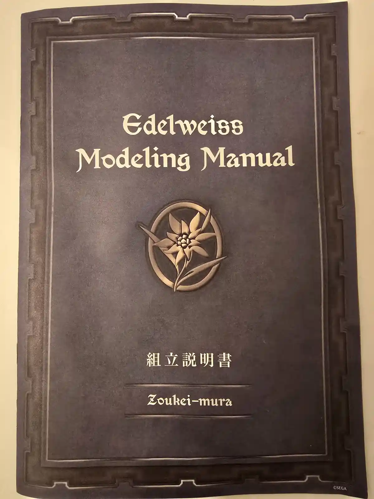 The image shows the cover of a dark brown manual with embossed text and a circular emblem featuring an edelweiss flower. The…