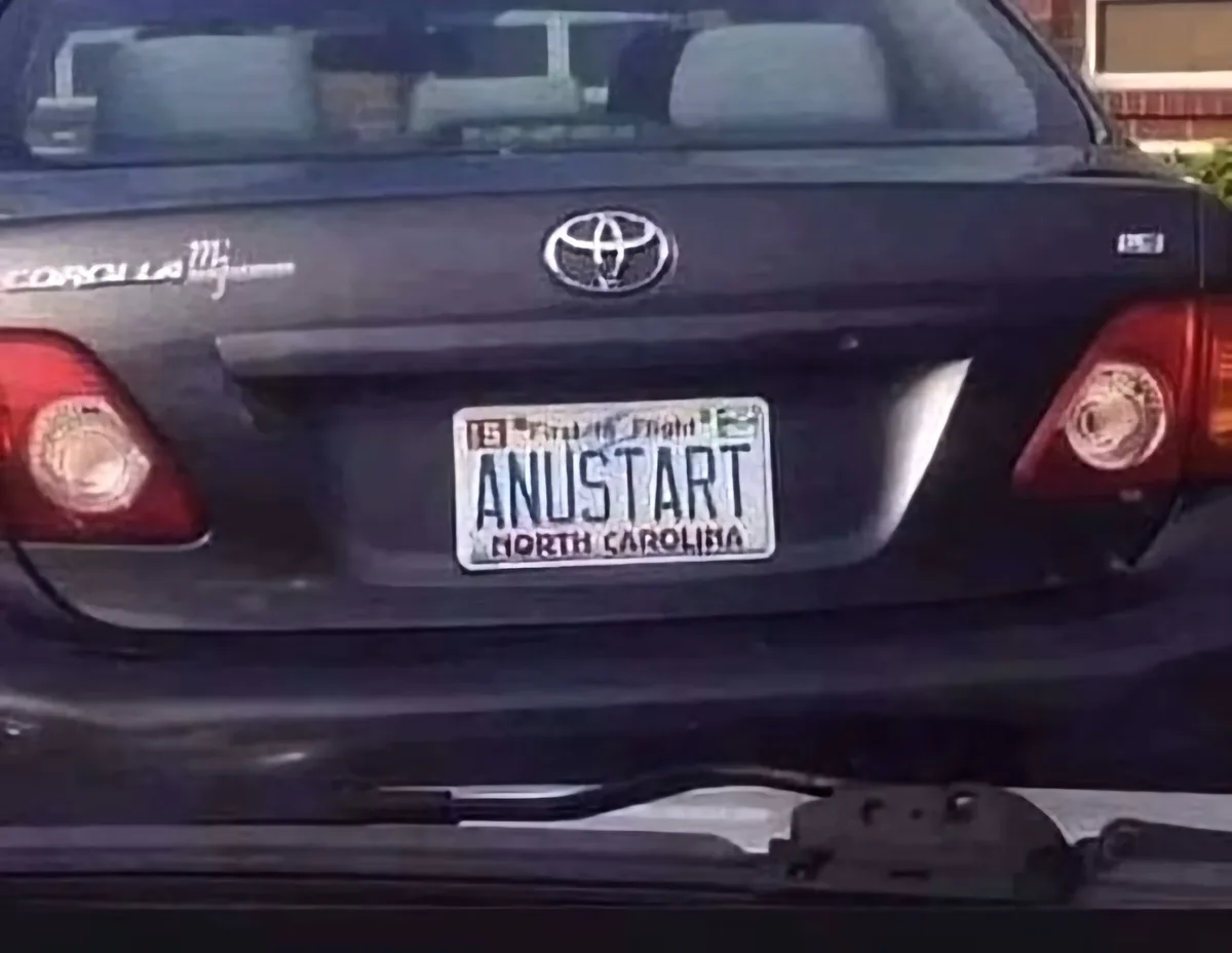 The rear of a dark-colored Toyota Corolla shows a North Carolina license plate with the text 'ANUSTART' clearly visible. The…