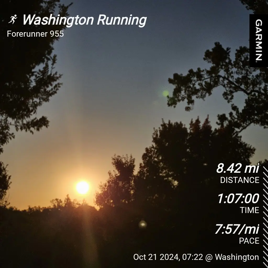 A screenshot of a Garmin Forerunner 955 running watch displaying a workout summary over a scenic sunrise photo framed by…