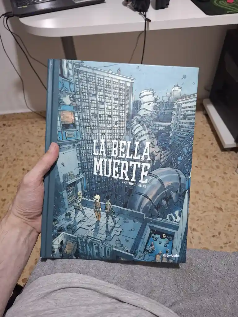 A person holds a graphic novel titled 'LA BELLA MUERTE' by Mathieu Bablet, featuring a blue-toned cover illustration of…