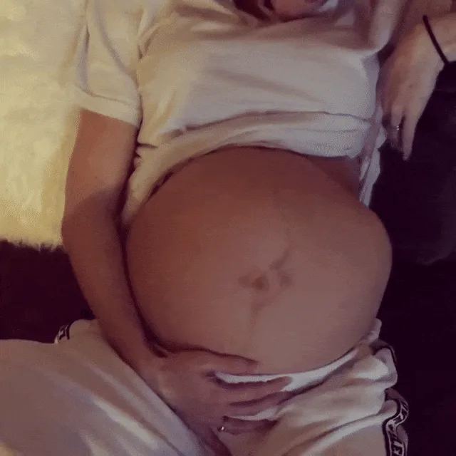 A grid of six identical photos shows a pregnant woman lying down, her white t-shirt pulled up to reveal her large belly. A…