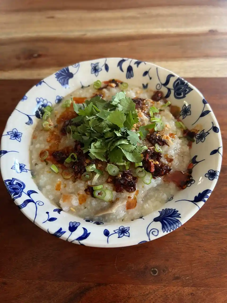 A close-up photo shows a white ceramic bowl with blue floral patterns, filled with a creamy, textured dish resembling rice…