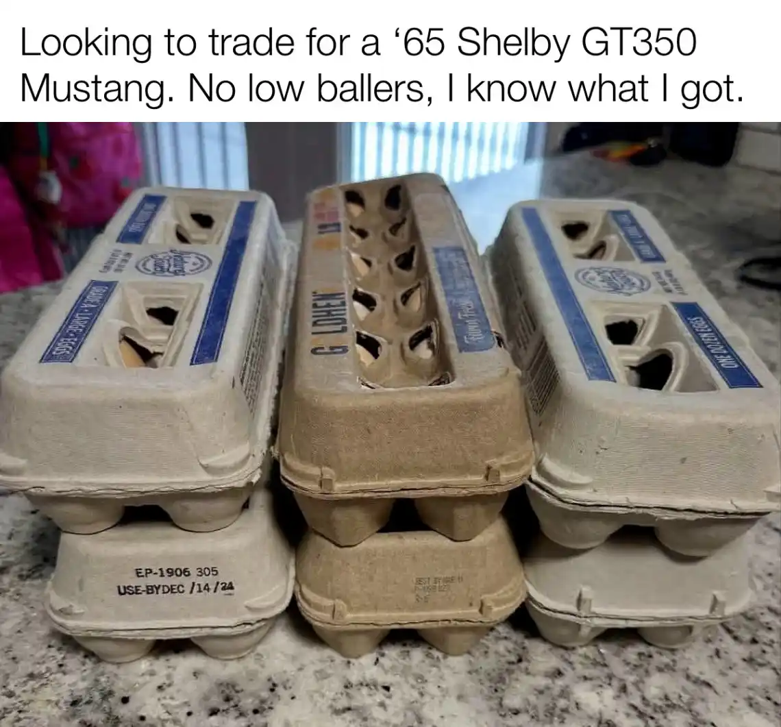 Three empty cardboard egg cartons are stacked on a speckled countertop, with the middle one visibly damaged and missing…