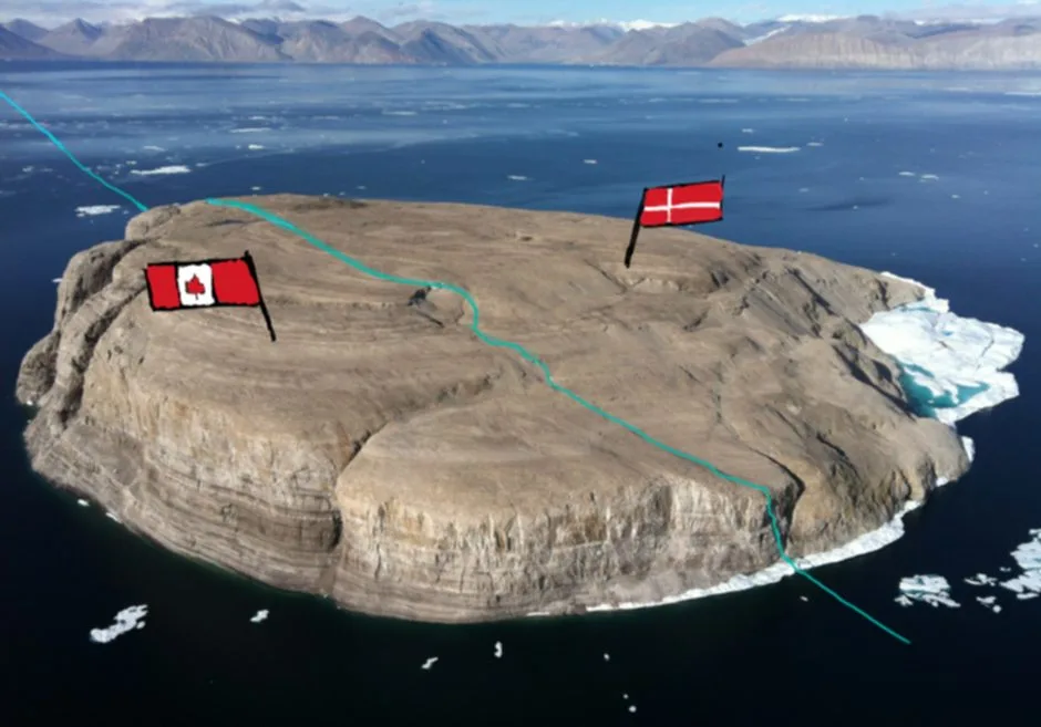 An aerial photo of a small, rocky island surrounded by icy waters and distant mountains. Two flags are digitally added: the…