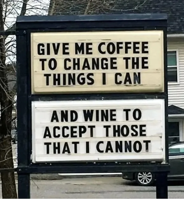 An outdoor sign with two lighted panels displays a humorous twist on a famous quote. The top panel reads 'GIVE ME COFFEE TO…