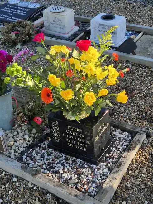 A black granite gravestone for Terry Carter, dated 17.1.35 - 13.6.98, with the inscription 'REST EASY MY LOVE' and 'OUR…