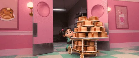 A sequence of frames from an animated film shows a young girl pushing a cart piled high with pancakes. She starts with a…