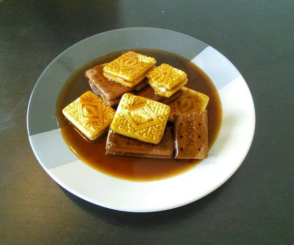 a plate of square biscuits, some golden and some brown, submerged in a dark brown liquid resembling gravy or sauce. The text…