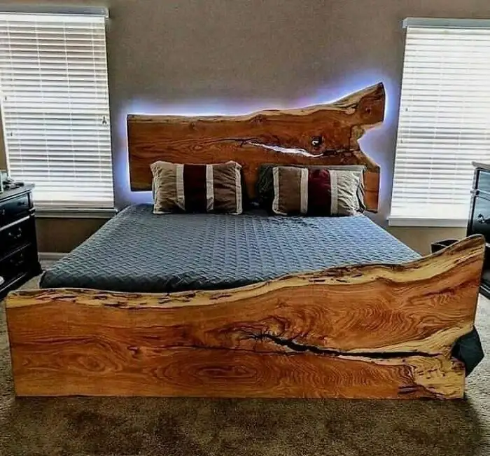 a bedroom features a large bed with a rustic, live-edge wooden headboard and footboard, both showcasing natural wood grain…
