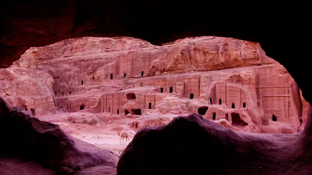 In the Jordanian desert basin, ancient Petra's tombs and temples emerge from the pinkish sandstone landscape. Carved into…
