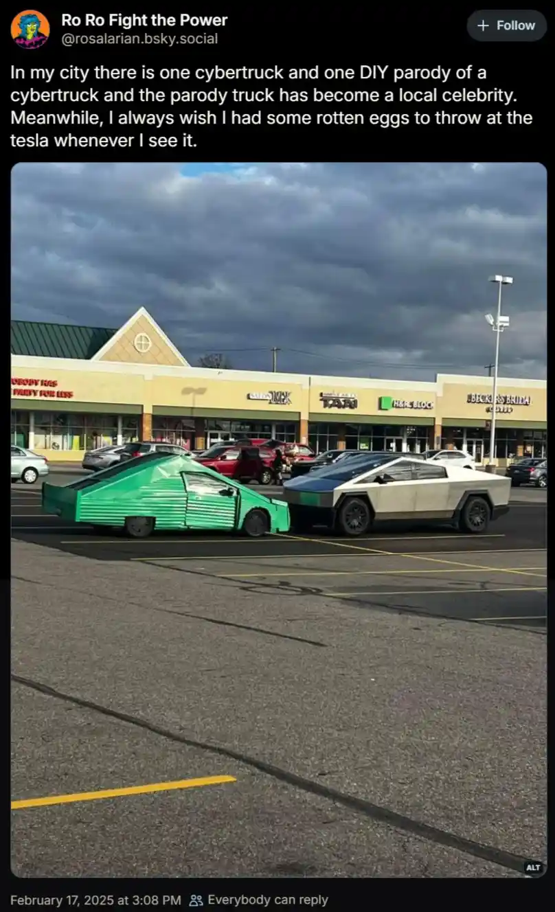 Two vehicles are parked side-by-side in a shopping mall parking lot under a cloudy sky. One is a real Tesla Cybertruck with…