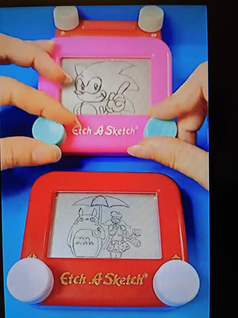Two Etch A Sketch toys are shown side by side, one pink and one red, each displaying a hand-drawn image. The top pink one…