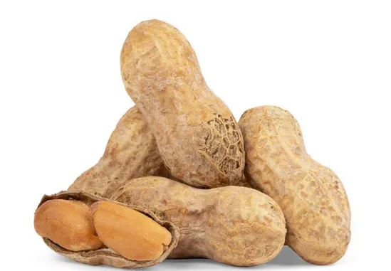 A pile of whole peanuts in their shells, one cracked open to reveal two peanut halves, against a plain white background. The…
