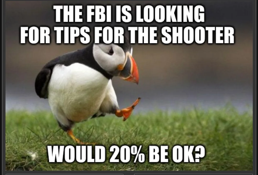 A penguin-like bird with black and white feathers, orange beak and feet, is standing on green grass and looking down while…