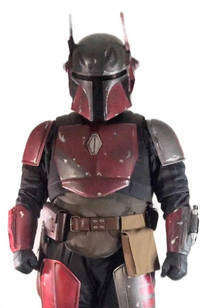 A person in a full-body Boba Fett costume, featuring a helmet with two antennae, red and black armor with weathered paint…