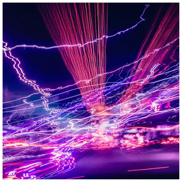 A long-exposure photograph captures vibrant streaks of pink, purple, and white light against a dark background, resembling…