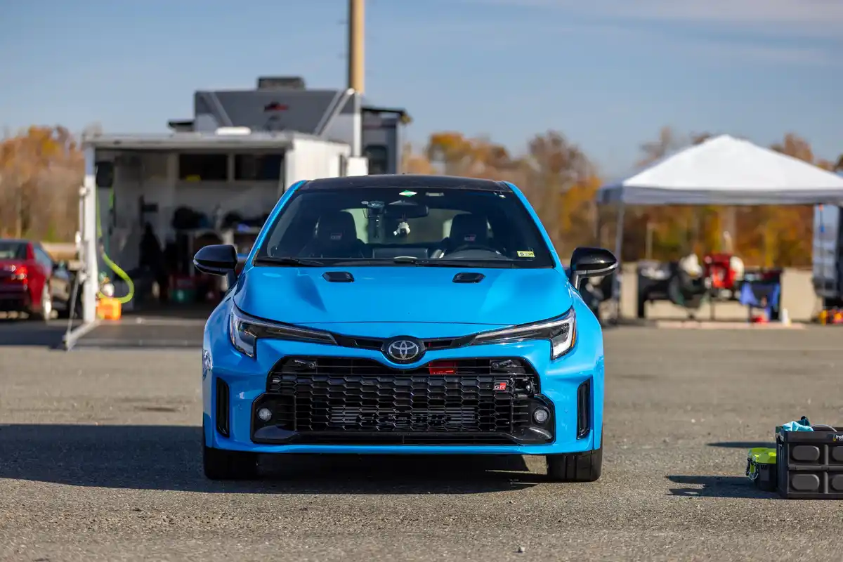 A bright blue Toyota GR Corolla is parked outdoors, facing the camera with its aggressive front grille and headlights…