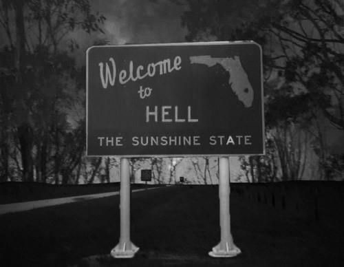 A black-and-white photo of a roadside sign that reads 'Welcome to HELL THE SUNSHINE STATE', with a silhouette of Florida…
