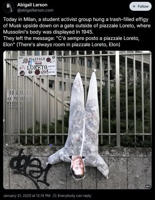 An upside-down, trash-filled effigy of Elon Musk hangs from a metal fence gate. The effigy is made of a clear plastic bag…
