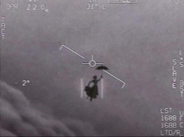 A grayscale thermal or night-vision image shows a person in a dark dress holding an umbrella, centered in a targeting…
