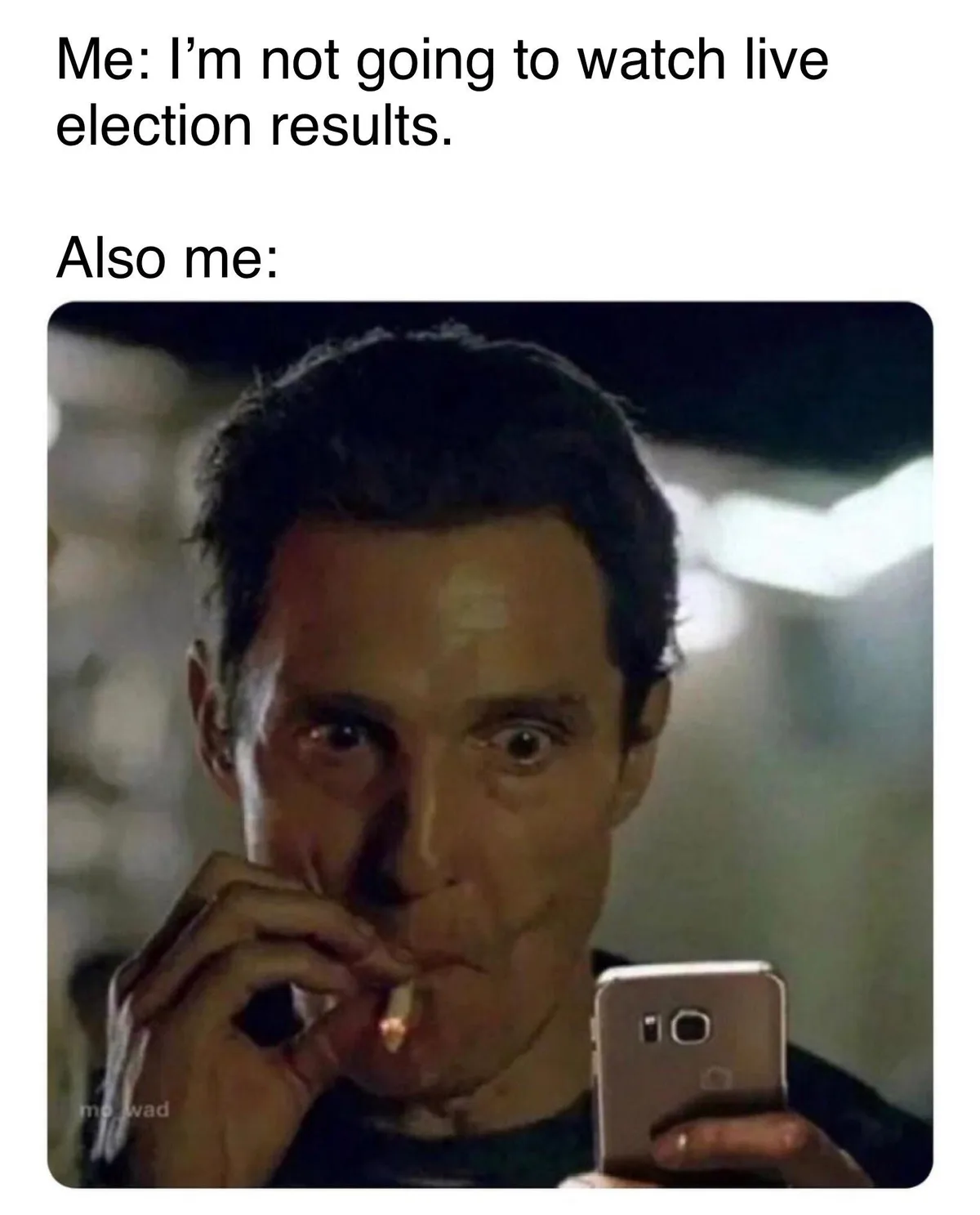 A man with wide, startled eyes holds a lit cigarette in one hand and a smartphone in the other, looking at the phone's…