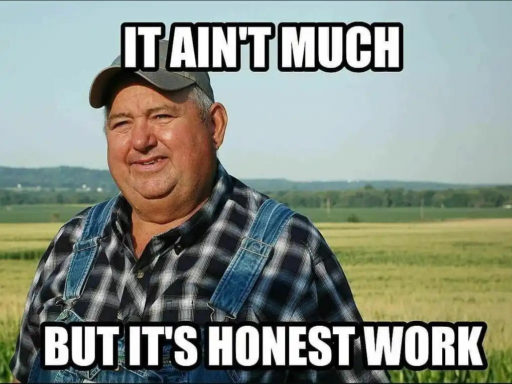 A middle-aged man wearing a plaid shirt and denim overalls stands in a field with hills in the background. He has a slight…